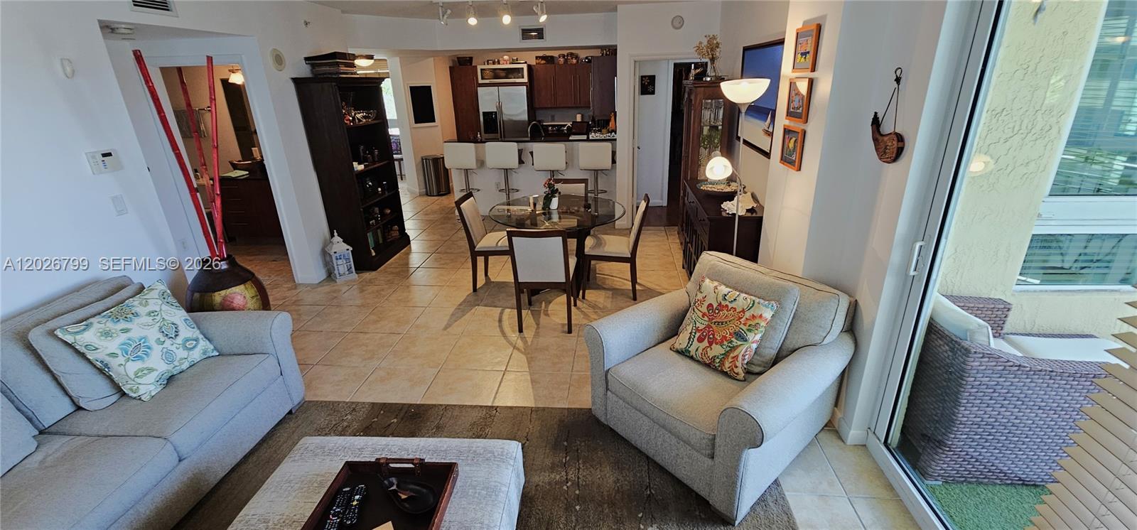 This open-concept living and dining area features tile flooring, neutral furniture, and a kitchen island — 7350 SW 89th St # 701S, Miami FL 33156, MIAMI, FL