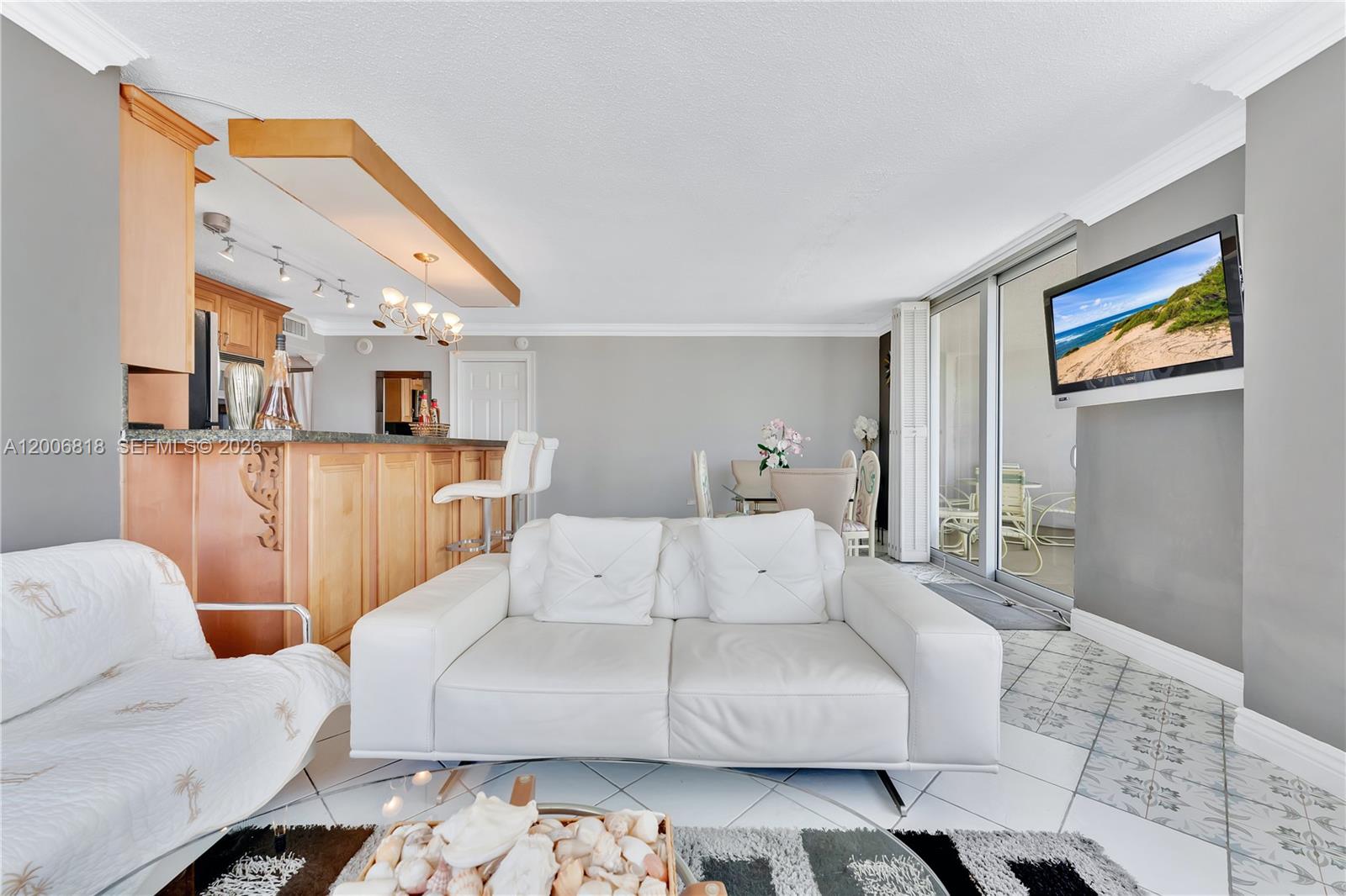 A living room features a white sofa, a breakfast bar, and a wall-mounted television — 5555 Collins Ave # 16A, Miami Beach FL 33140, MIAMI BEACH, FL