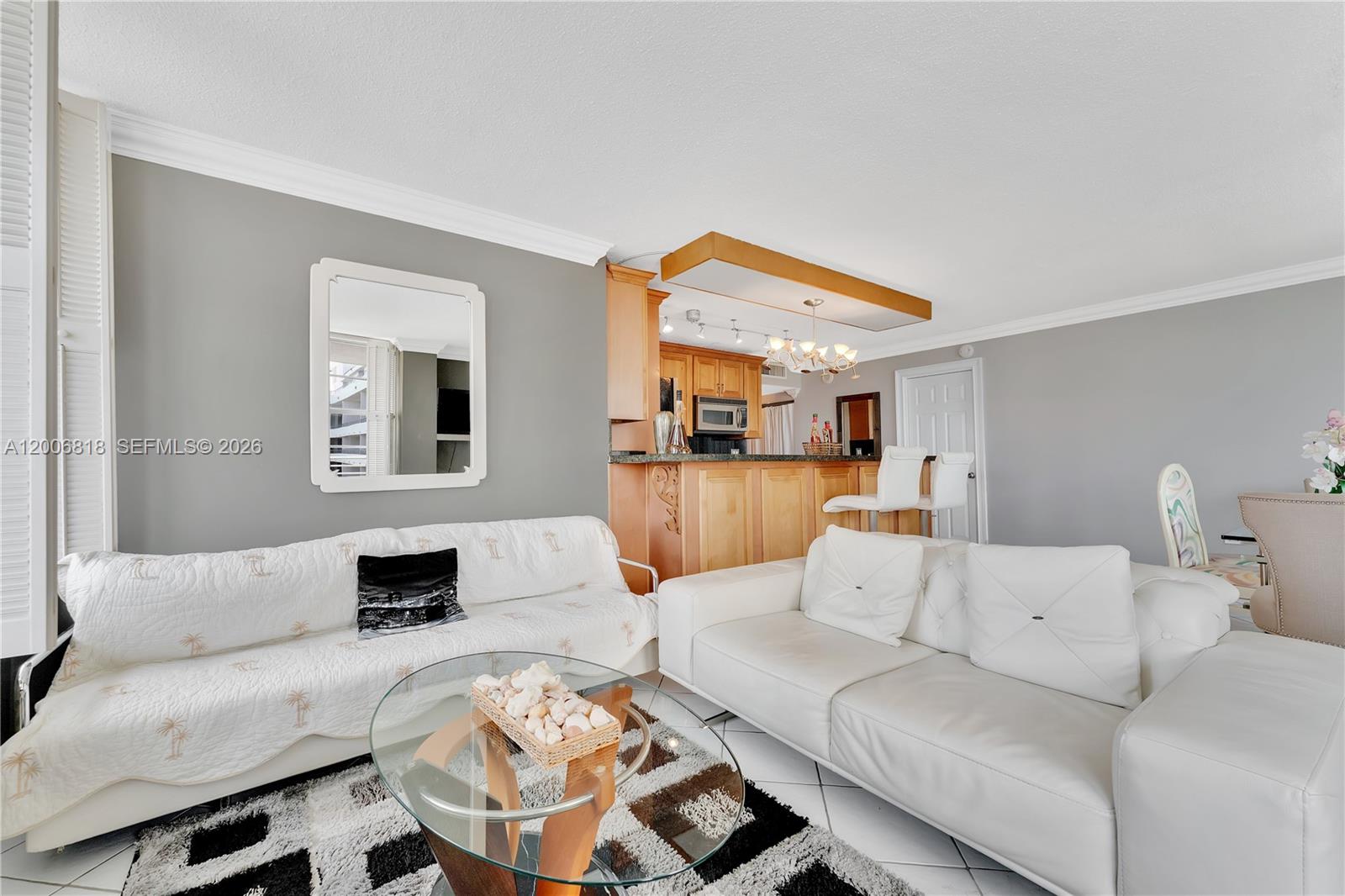 A living room features two white sofas, a glass coffee table, and a kitchen bar — 5555 Collins Ave # 16A, Miami Beach FL 33140, MIAMI BEACH, FL