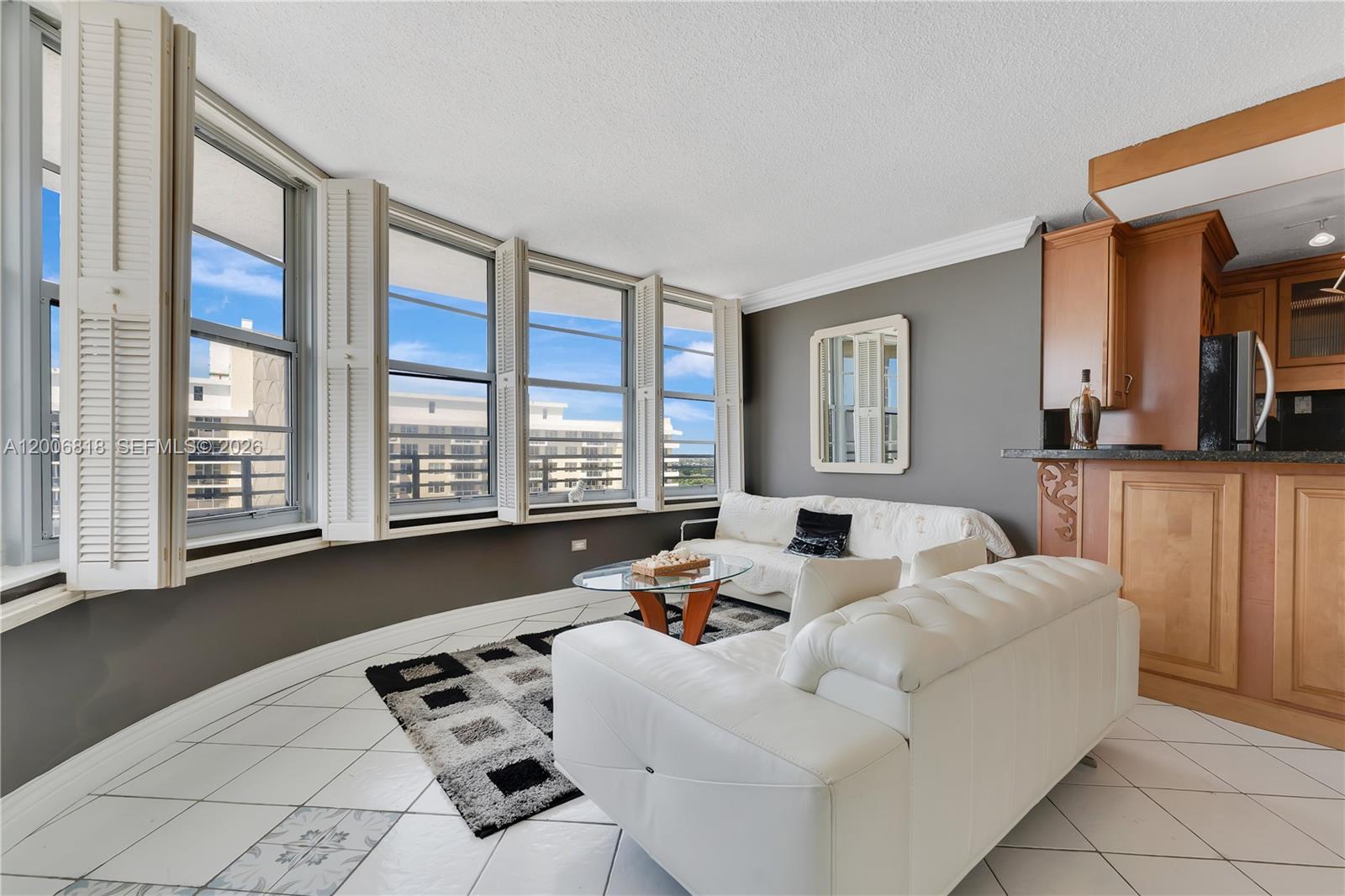 A living room features white tile floors, a white sofa, and large windows with shutters — 5555 Collins Ave # 16A, Miami Beach FL 33140, MIAMI BEACH, FL