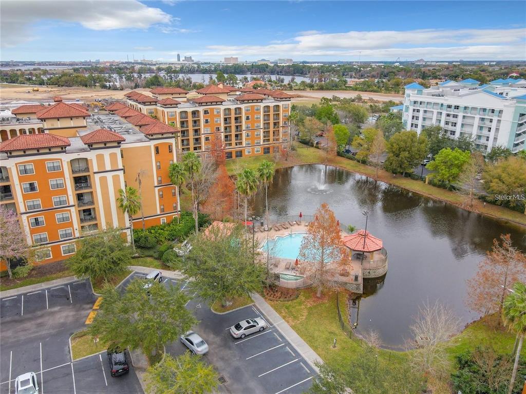 An aerial view shows a multi-story apartment building, a swimming pool, and a small lake — 12544 FLORIDAYS RESORT DR UNIT 202B, ORLANDO, FL