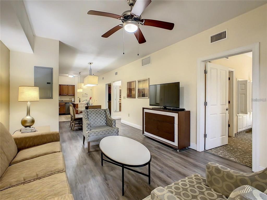 A living room with wood-look flooring, a ceiling fan, and an adjacent dining area — 12544 FLORIDAYS RESORT DR UNIT 202B, ORLANDO, FL