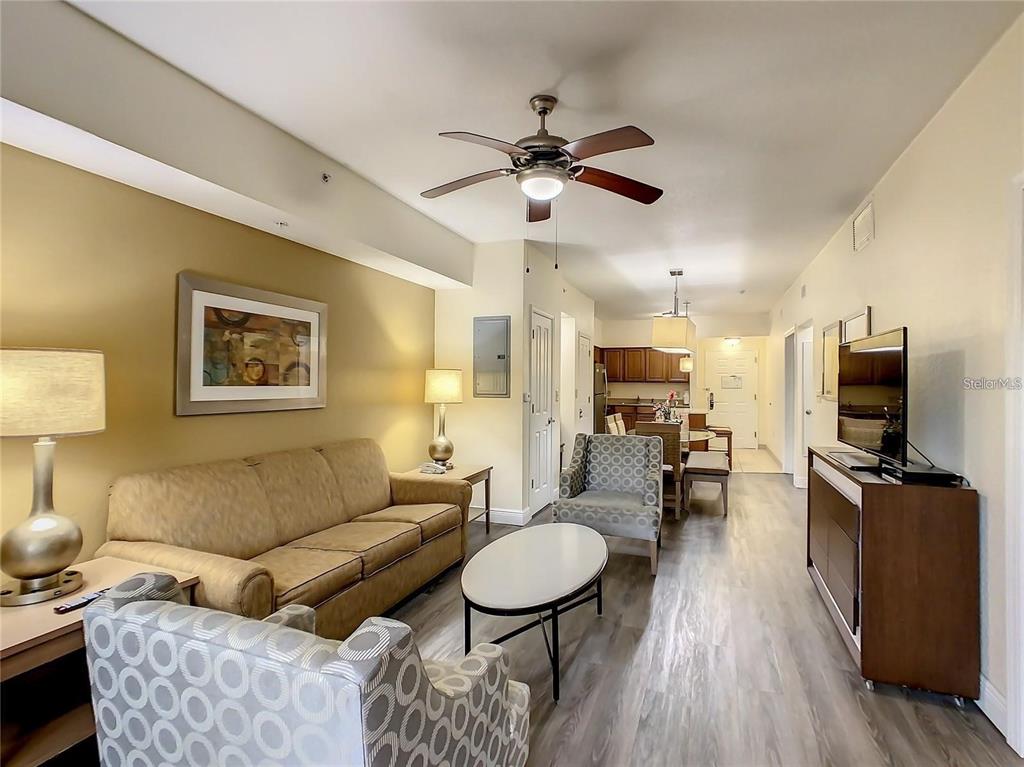 A living room with a sofa, patterned armchairs, a coffee table, and wood-look flooring — 12544 FLORIDAYS RESORT DR UNIT 202B, ORLANDO, FL