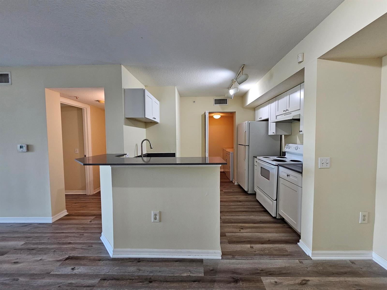 A kitchen features white cabinets, white appliances, a dark countertop, and wood-look flooring — 604 Villa Circle # 604, Boynton Beach FL 33435, BOYNTON BEACH, FL