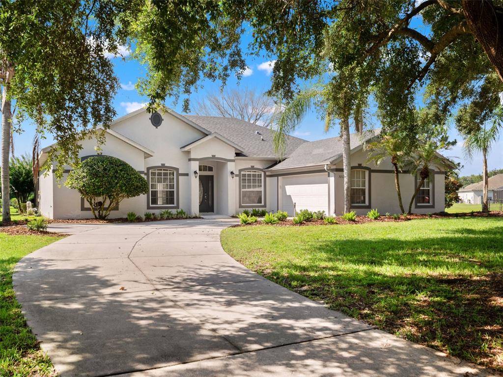 A single-story house with a concrete driveway, gray trim, and a manicured lawn — 5809 GUENEVERE COURT, ST CLOUD, FL