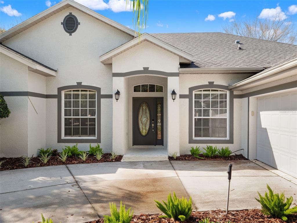 A single-story house with a white stucco exterior, grey trim, and a concrete driveway — 5809 GUENEVERE COURT, ST CLOUD, FL
