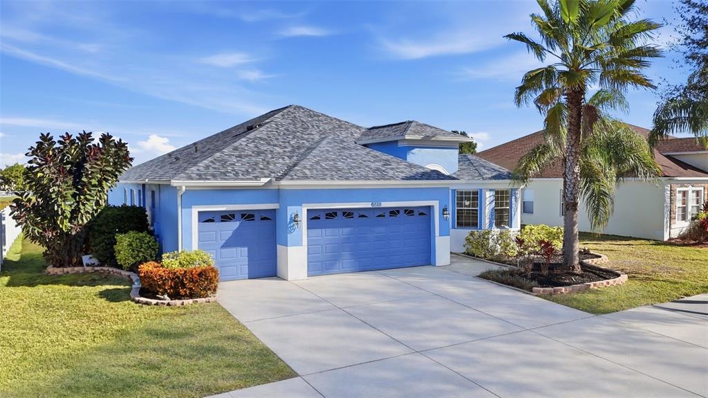 A blue single-story house with a three-car garage and a palm tree in the front yard — 13230 GRAHAM YARDEN DRIVE, RIVERVIEW, FL