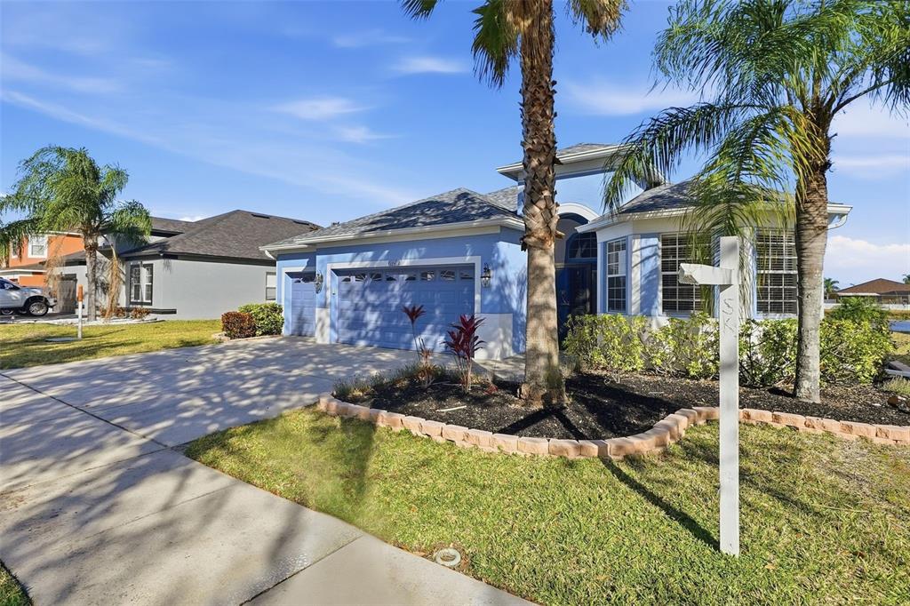 A blue single-story house with a three-car garage and palm trees in the front yard — 13230 GRAHAM YARDEN DRIVE, RIVERVIEW, FL