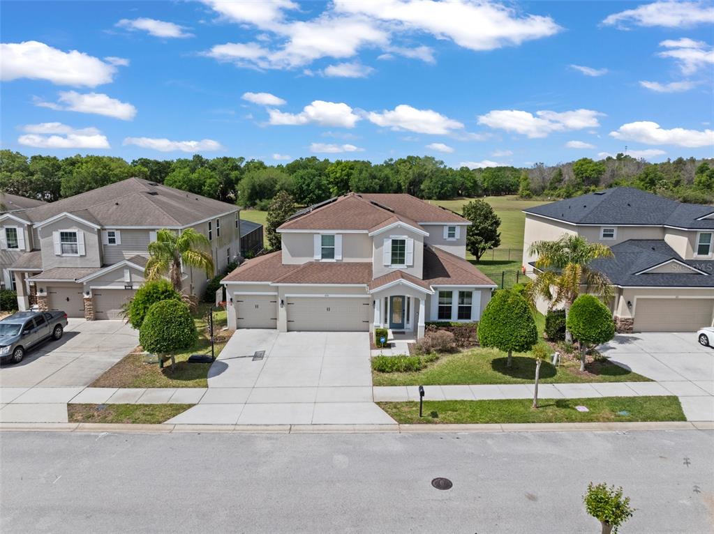An aerial view of a two-story suburban house with a three-car garage and driveway — 635 NEPTUNE DRIVE, GROVELAND, FL