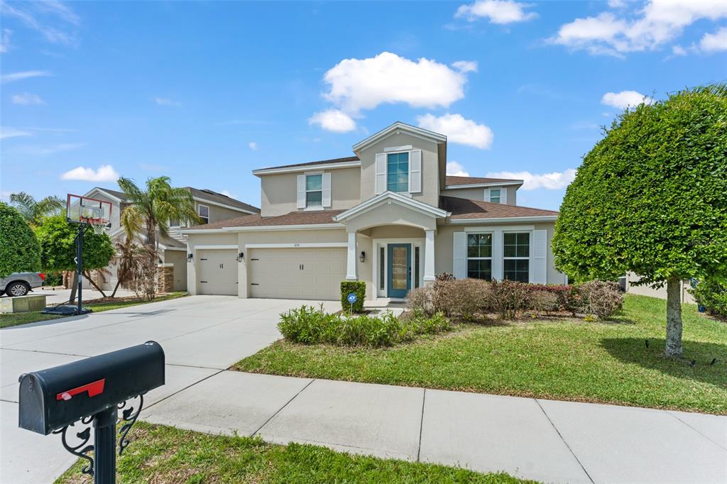 A two-story suburban house with a three-car garage, a front porch, and a driveway — 635 NEPTUNE DRIVE, GROVELAND, FL