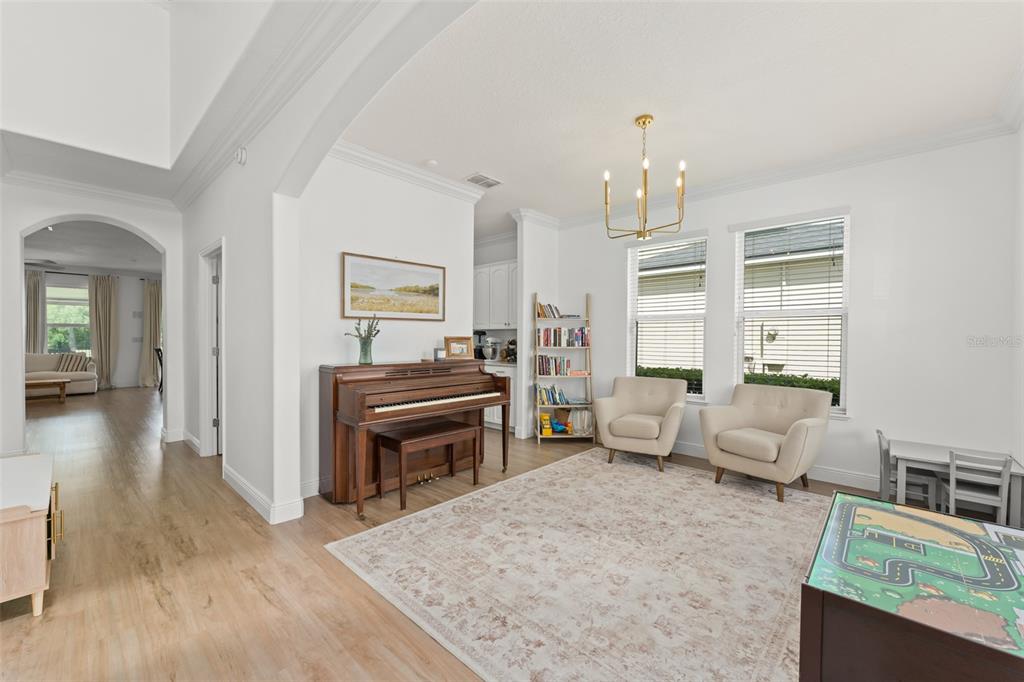 A living room features a piano, two armchairs, a bookshelf, and a play table — 635 NEPTUNE DRIVE, GROVELAND, FL