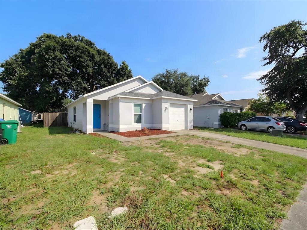 A single-story house with a blue front door, a white garage, and a patchy lawn — 7047 HICKORY BRANCH CIRCLE, ORLANDO, FL