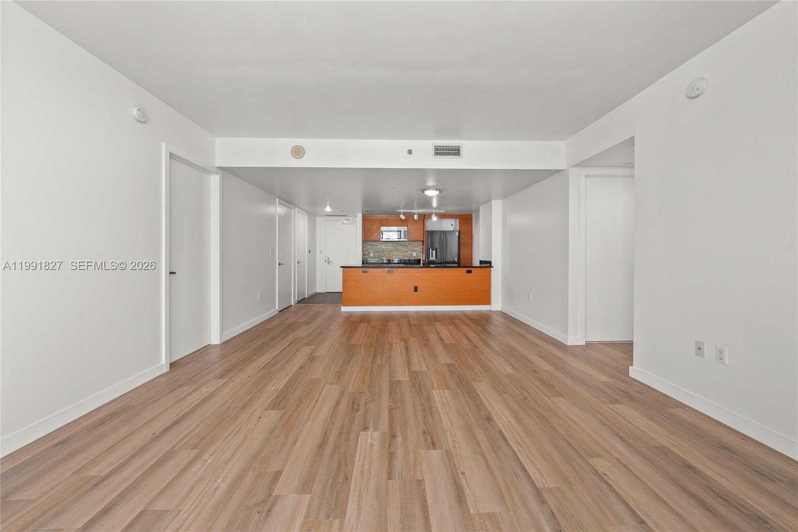 An open-concept living area features light wood-look flooring and a kitchen with wood cabinetry — 50 Biscayne Blvd # 4111, Miami FL 33132, MIAMI, FL