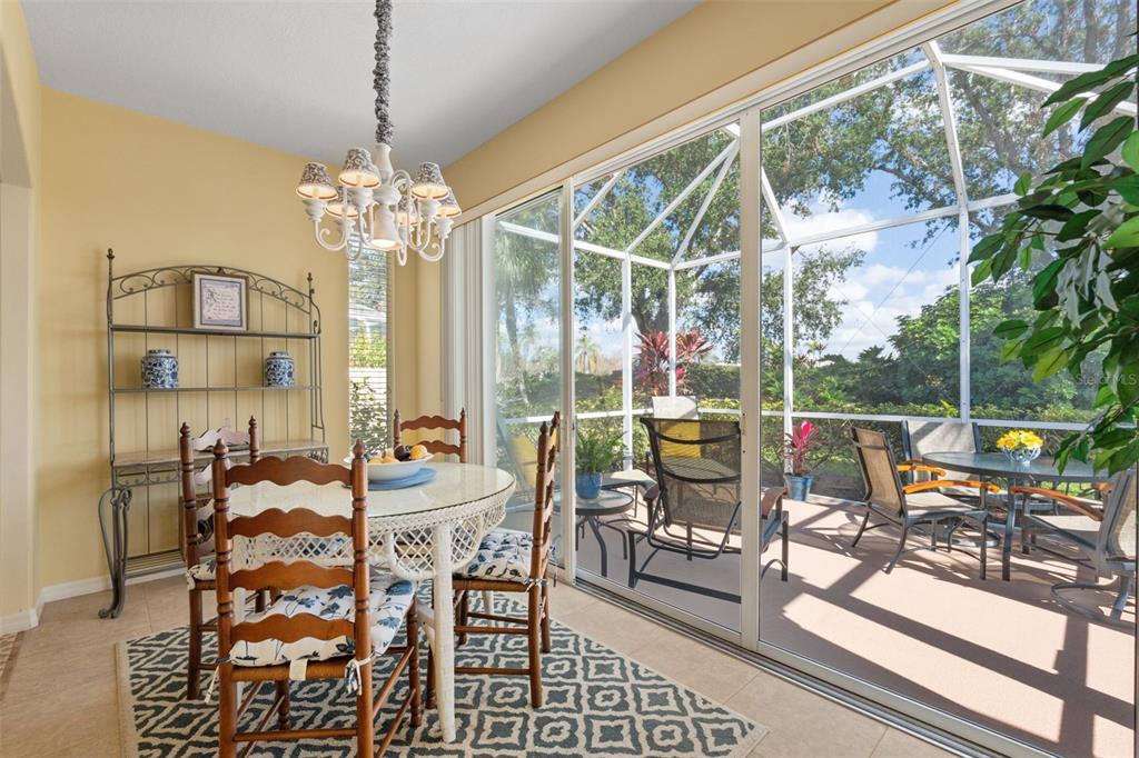 A dining area with a white chandelier and table leads into a living room — 905 BARCLAY COURT, VENICE, FL