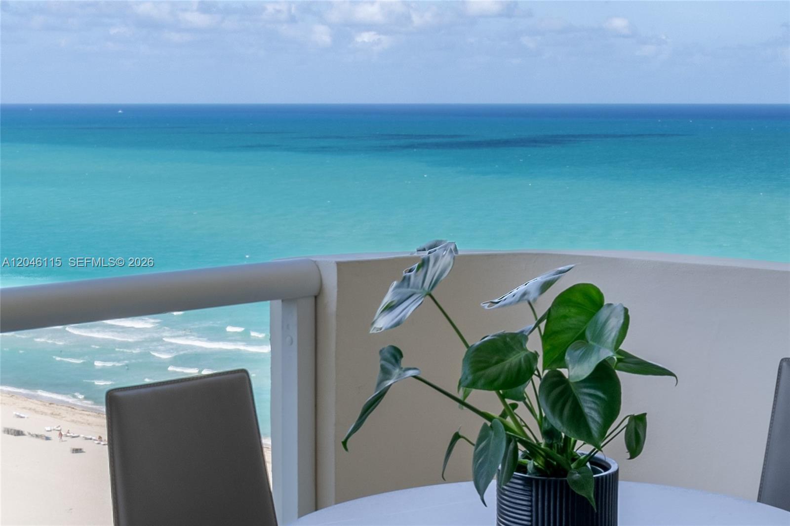 A potted plant sits on a balcony table overlooking the ocean and beach — 5757 Collins Ave # 2207, Miami Beach FL 33140, MIAMI BEACH, FL