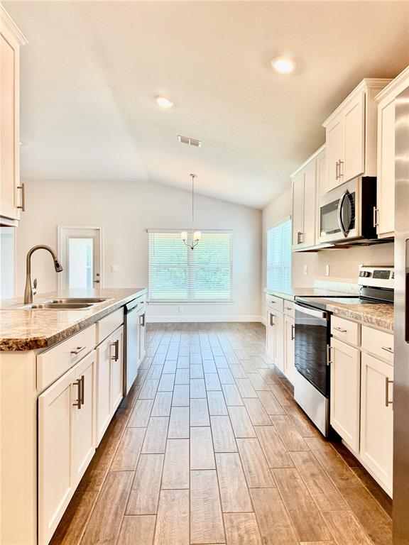 A kitchen with white cabinets, granite countertops, stainless steel appliances, and wood-look tile flooring — 633 W REXFORD DRIVE, BEVERLY HILLS, FL