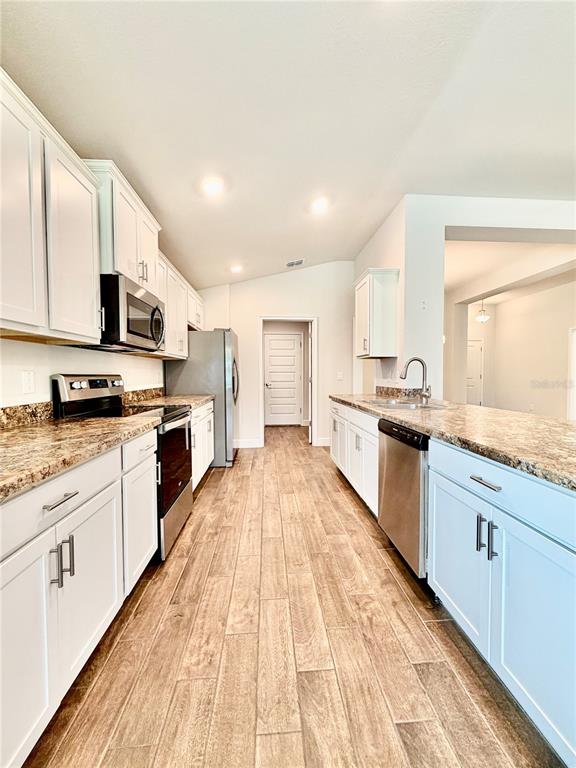 A kitchen features white cabinets, granite countertops, stainless steel appliances, and wood-look tile flooring — 633 W REXFORD DRIVE, BEVERLY HILLS, FL