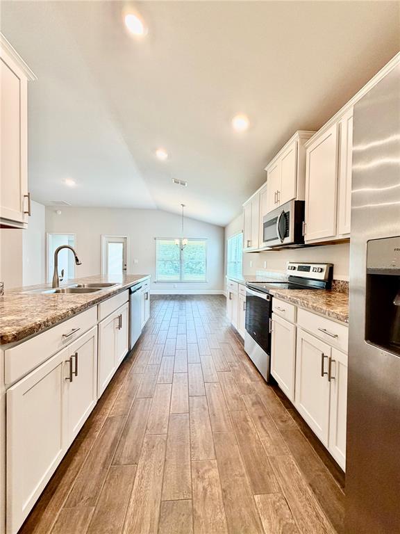 A kitchen features white cabinets, granite countertops, stainless steel appliances, and wood-look tile flooring — 633 W REXFORD DRIVE, BEVERLY HILLS, FL