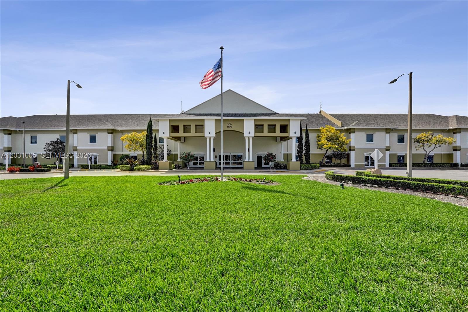 A large, two-story commercial building with a central entrance and an American flag — 47 Camden # B, West Palm Beach FL 33417, WEST PALM BEACH, FL