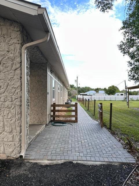 A paved walkway leads along the side of a house with stone siding and gutters — 651 NE 60th Avenue, Okeechobee FL 34974, OKEECHOBEE, FL