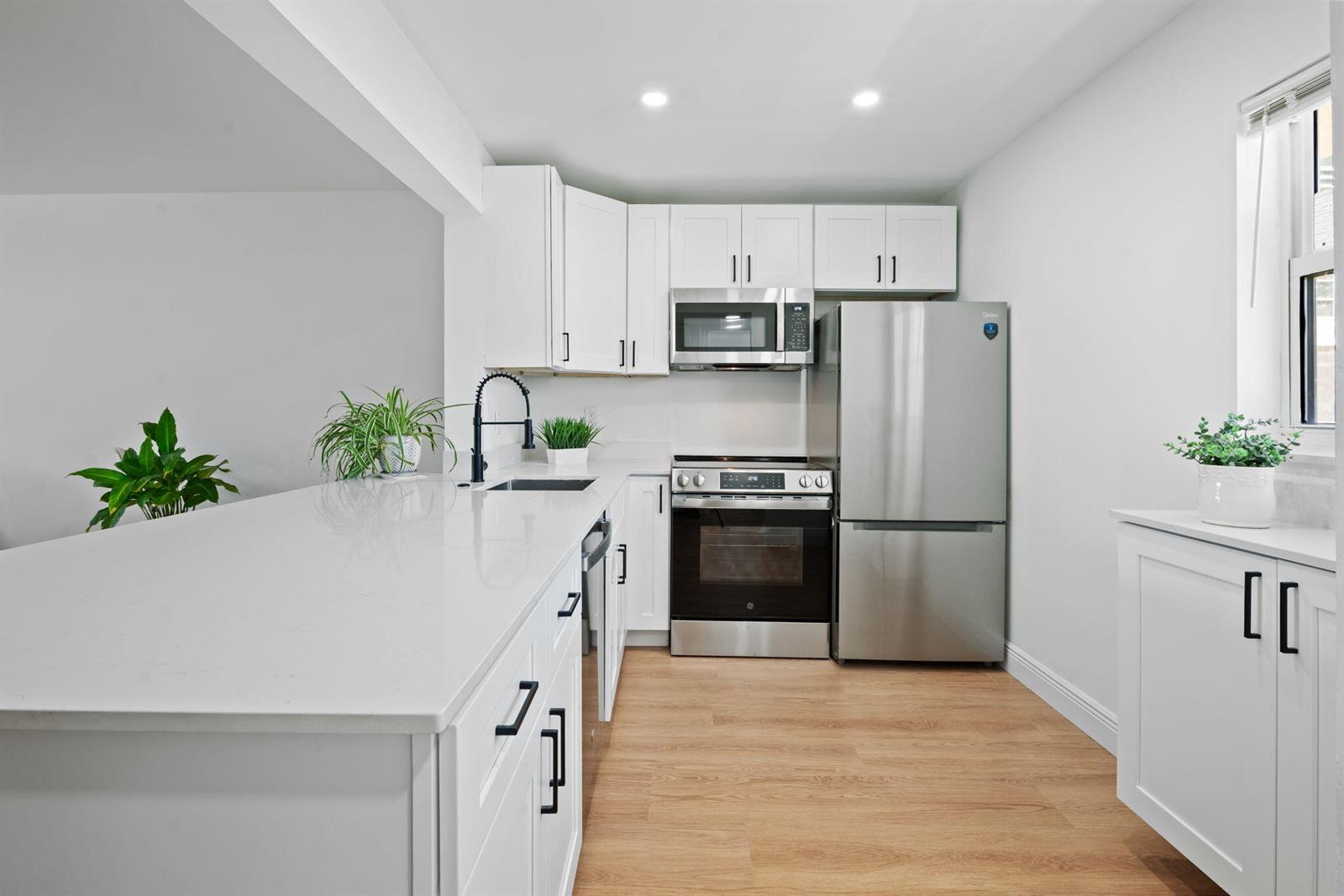 A modern kitchen features white cabinets, stainless steel appliances, and a large white island — 230 NE 26th Avenue # 2160, Boynton Beach FL 33435, BOYNTON BEACH, FL