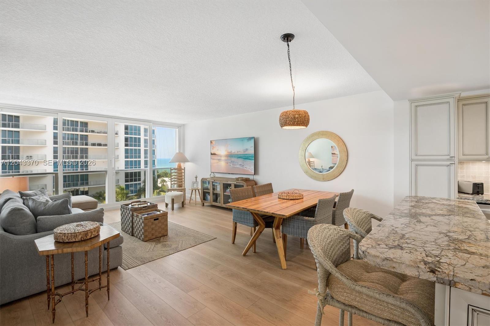 An open-concept living and dining area features light wood floors, coastal decor, and ocean views — 3505 S Ocean Dr # 708, Hollywood FL 33019, HOLLYWOOD, FL