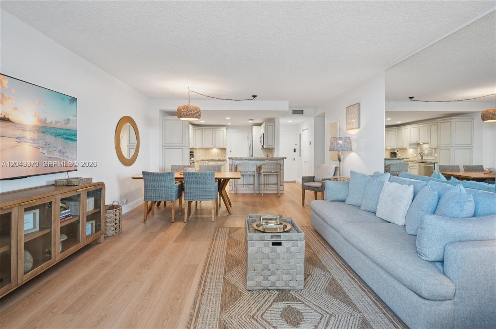 An open-concept living and dining area features light wood floors, a blue sofa, and kitchen — 3505 S Ocean Dr # 708, Hollywood FL 33019, HOLLYWOOD, FL