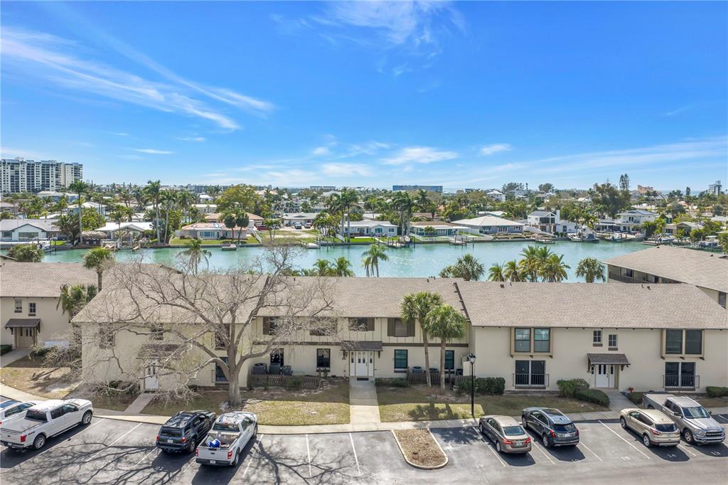 An aerial view shows a multi-story apartment building with a parking lot and waterfront — 509 PLAZA SEVILLE COURT UNIT 19, TREASURE ISLAND, FL
