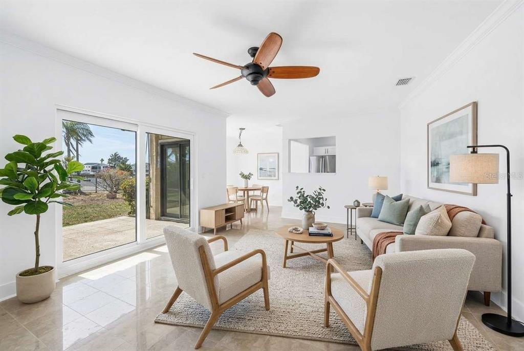 A bright living room features light tile floors, a wooden ceiling fan, and sliding glass doors — 509 PLAZA SEVILLE COURT UNIT 19, TREASURE ISLAND, FL