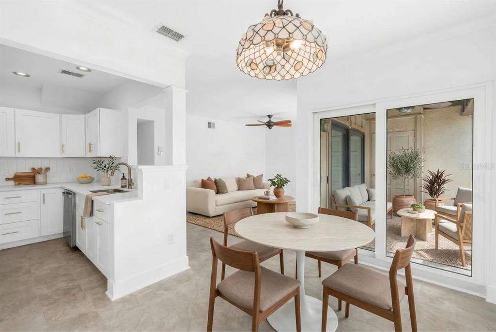 A bright open-concept kitchen, dining area, and living room with white cabinets and patio access — 509 PLAZA SEVILLE COURT UNIT 19, TREASURE ISLAND, FL