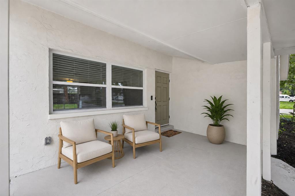 A covered front porch features two chairs, a small table, and a potted plant — 9001 ARNDALE CIRCLE, TAMPA, FL