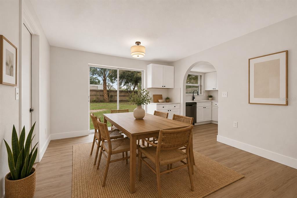 A dining room with a wooden table, woven chairs, and an arched doorway to the kitchen — 9001 ARNDALE CIRCLE, TAMPA, FL