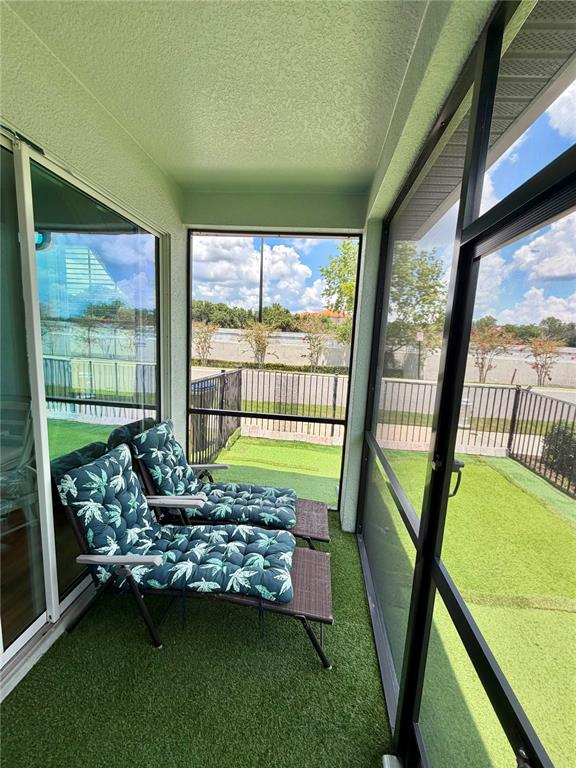 A screened-in porch features two lounge chairs with patterned cushions on artificial turf flooring — 7963 BOYDEN WAY, KISSIMMEE, FL