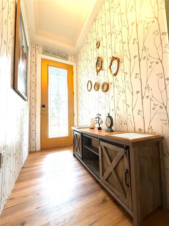 A hallway features wood-look flooring, tree-patterned wallpaper, a yellow door, and a wooden console table — 7963 BOYDEN WAY, KISSIMMEE, FL
