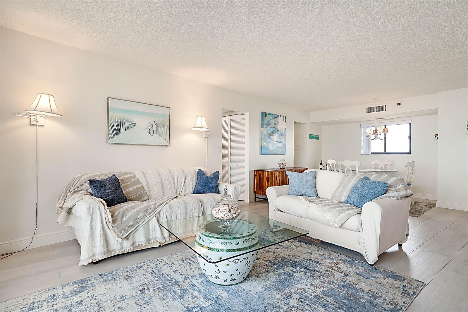 A living room features two sofas, a glass coffee table, and a blue area rug — 100 Ocean Trail Way # 1003, Jupiter FL 33477, JUPITER, FL