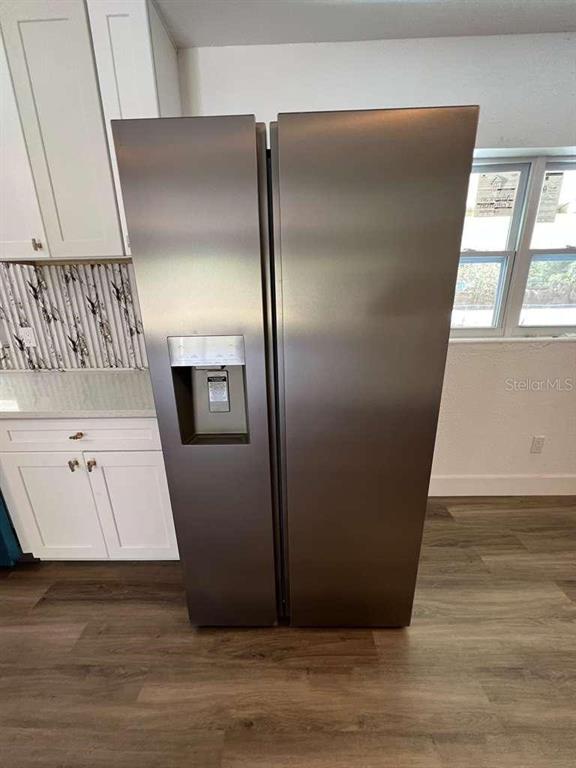 A stainless steel side-by-side refrigerator stands in a kitchen with white cabinets and wood-look flooring — 4217 WD JUDGE DRIVE UNIT W, ORLANDO, FL