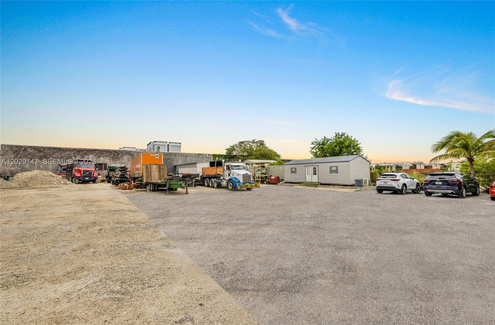 A gravel lot features a small modular building, several parked trucks, and two SUVs — 14760 NW 24th Ct, Opa-Locka FL 33054, OPA-LOCKA, FL