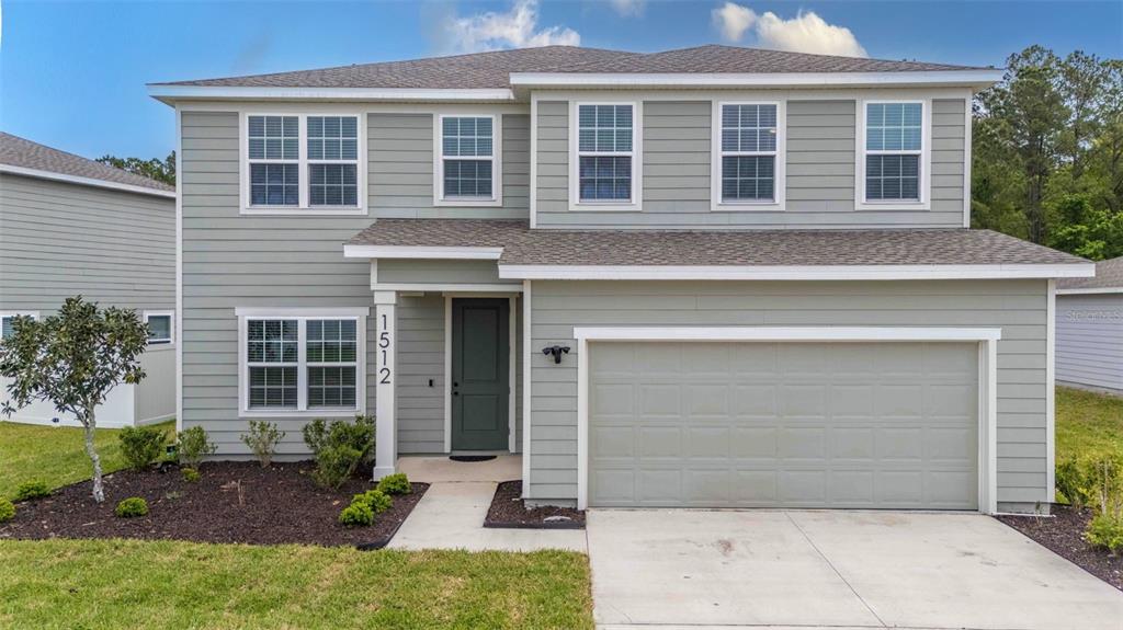 A two-story gray house with a two-car garage sits under a sunset sky — 1512 TAN TARA TRAIL, JACKSONVILLE, FL