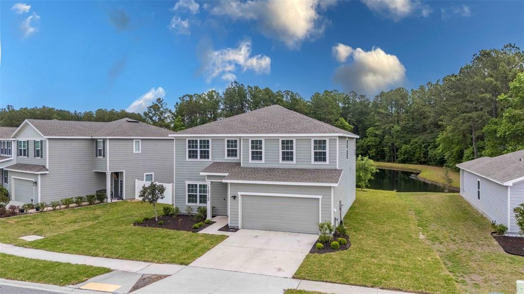 A two-story, light gray suburban house with a two-car garage and a backyard pond — 1512 TAN TARA TRAIL, JACKSONVILLE, FL