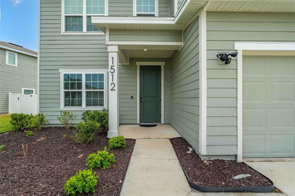 The exterior of a two-story house features light green siding, a dark door, and a walkway — 1512 TAN TARA TRAIL, JACKSONVILLE, FL