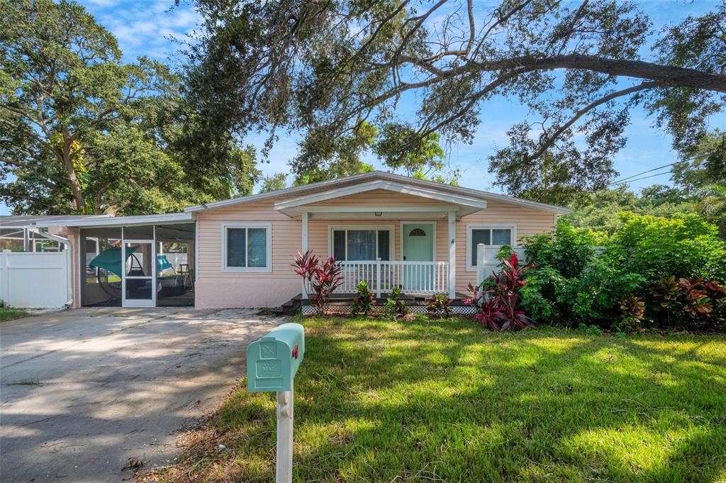 A light pink single-story house with a front porch, screened carport, and green mailbox — 1600 LORETTA AVENUE NW, LARGO, FL