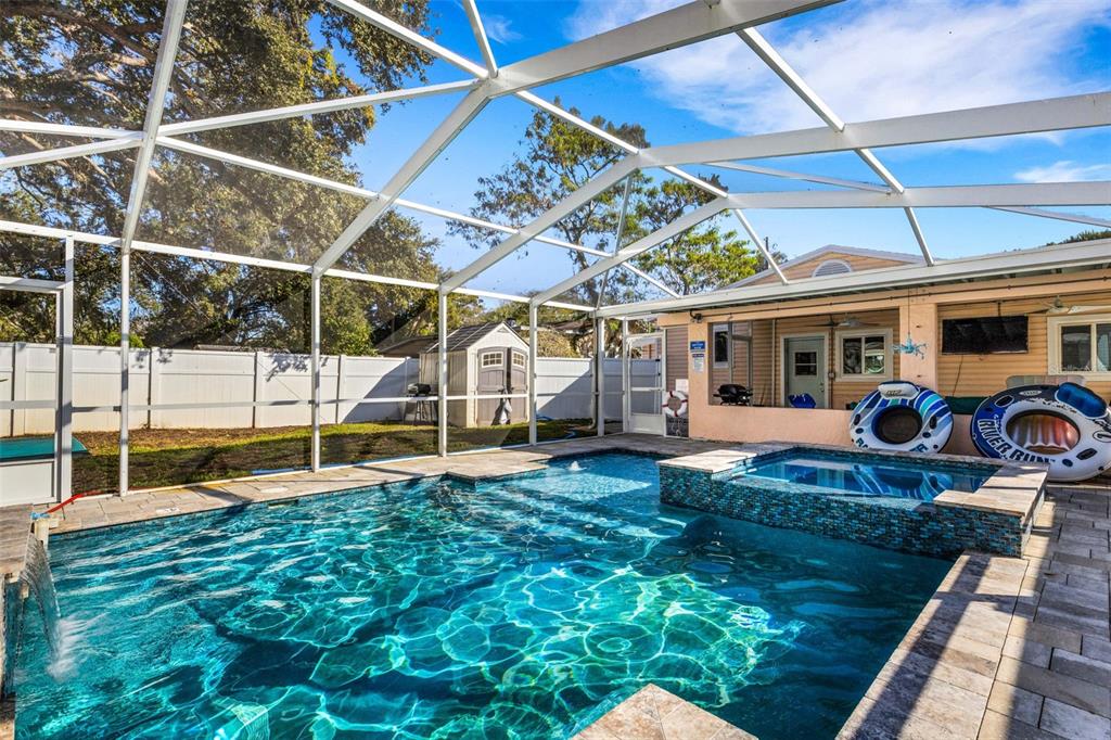 A screened-in swimming pool and raised spa sit on a patio behind a house — 1600 LORETTA AVENUE NW, LARGO, FL