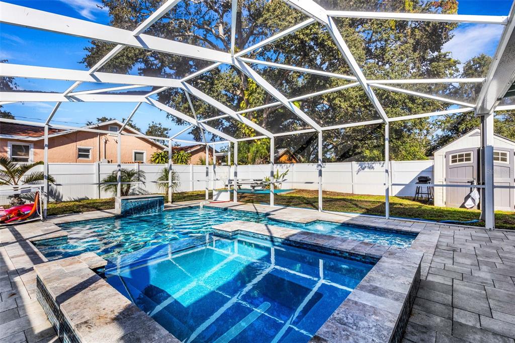 A screened-in backyard pool and spa with stone pavers and a white vinyl fence — 1600 LORETTA AVENUE NW, LARGO, FL
