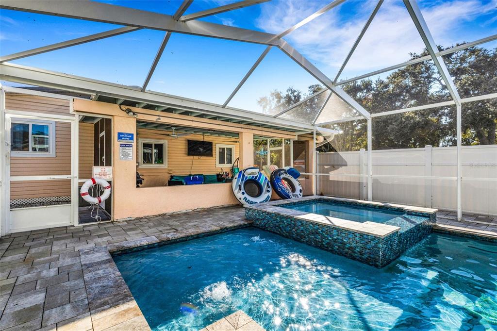 A screened-in patio features a swimming pool, a raised spa, and a covered seating area — 1600 LORETTA AVENUE NW, LARGO, FL