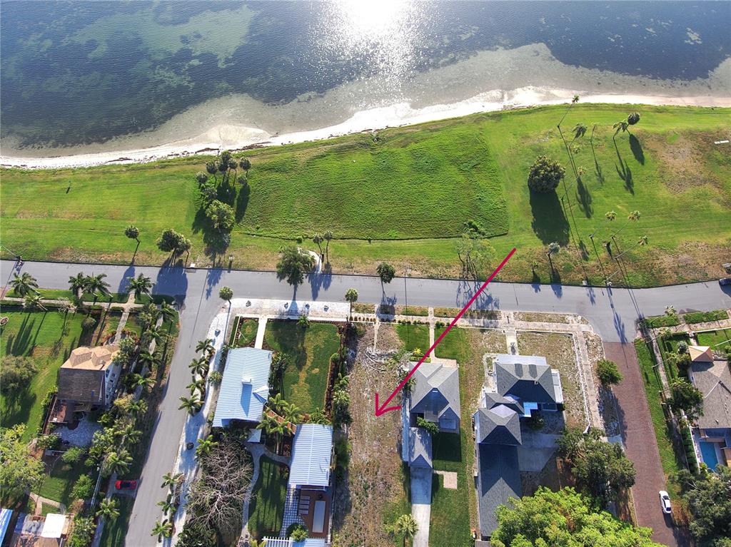 An aerial view shows a vacant residential lot situated between two houses near a waterfront — 1817 BEACH DRIVE SE, ST PETERSBURG, FL