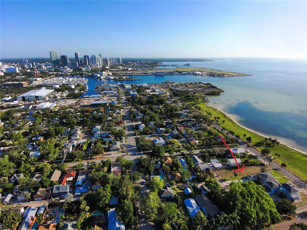 An aerial view shows a coastal neighborhood with a red arrow pointing to a vacant lot — 1817 BEACH DRIVE SE, ST PETERSBURG, FL