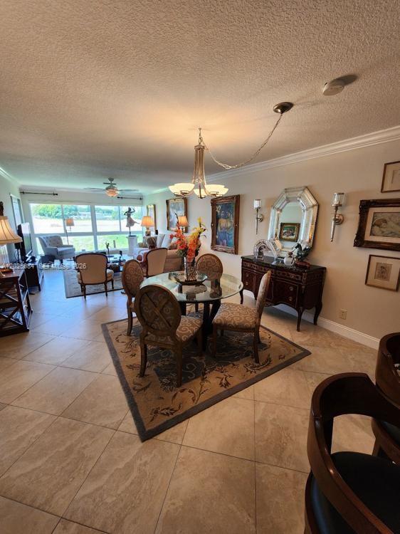 A dining area with a glass table and chairs sits in an open-concept living space — 5590 Via Delray # B, Delray Beach FL 33484, DELRAY BEACH, FL