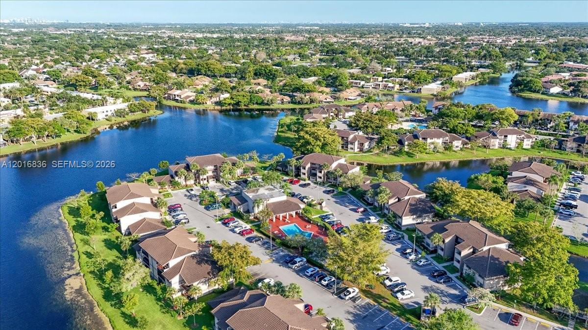 An aerial view shows a residential apartment complex with a pool and surrounding lakes — 9860 Nob Hill Ln # 9860, Sunrise FL 33351, SUNRISE, FL