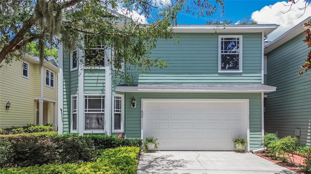 A two-story house with light green siding, a white garage door, and a concrete driveway — 822 LUMSDEN RESERVE DRIVE, BRANDON, FL