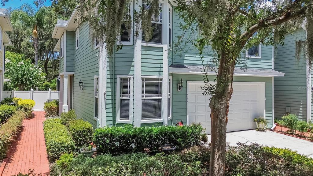 A two-story light green house with a white garage door and a brick walkway — 822 LUMSDEN RESERVE DRIVE, BRANDON, FL